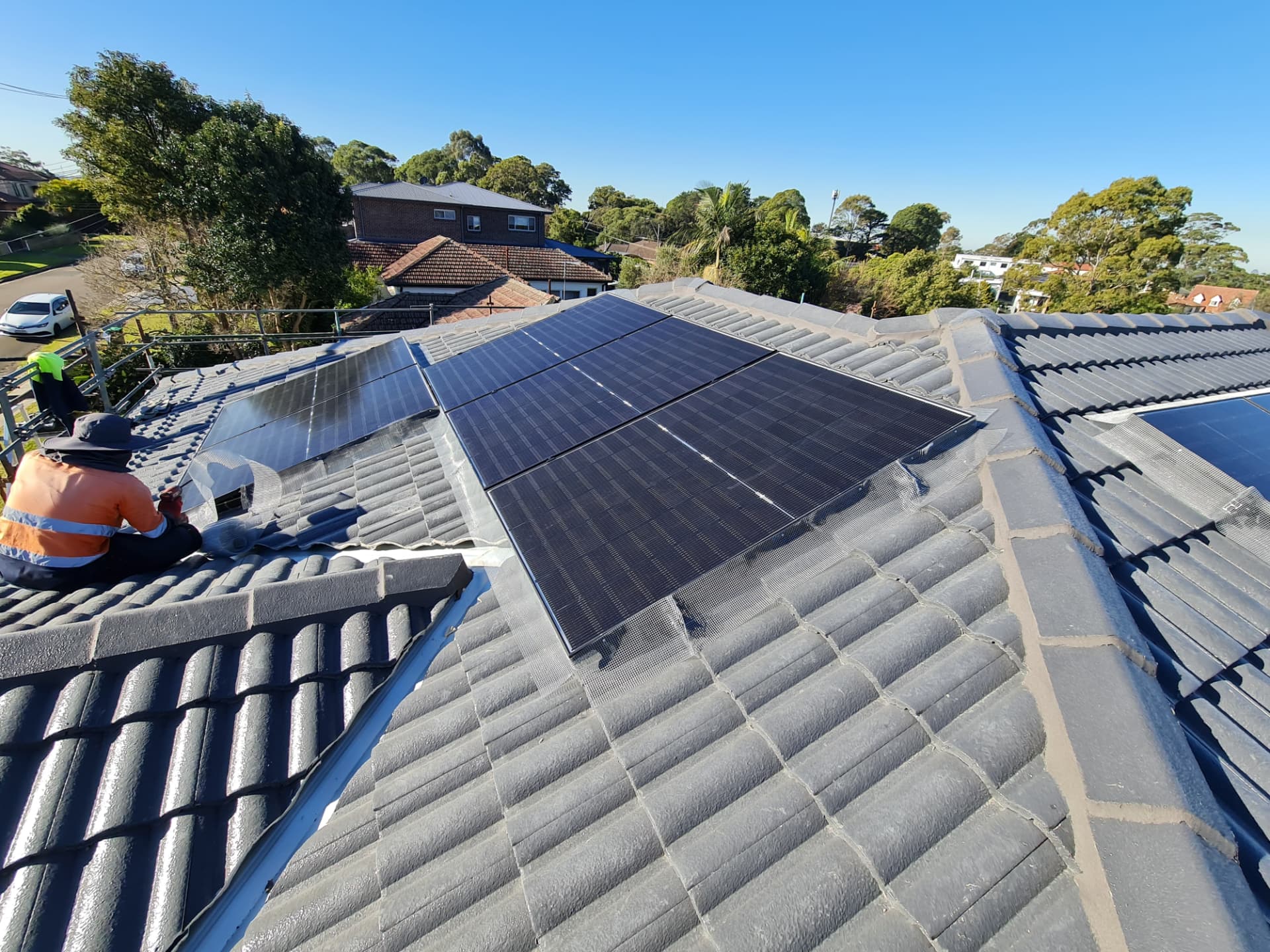 Bird mesh being installed around a solar array on a tiled roof